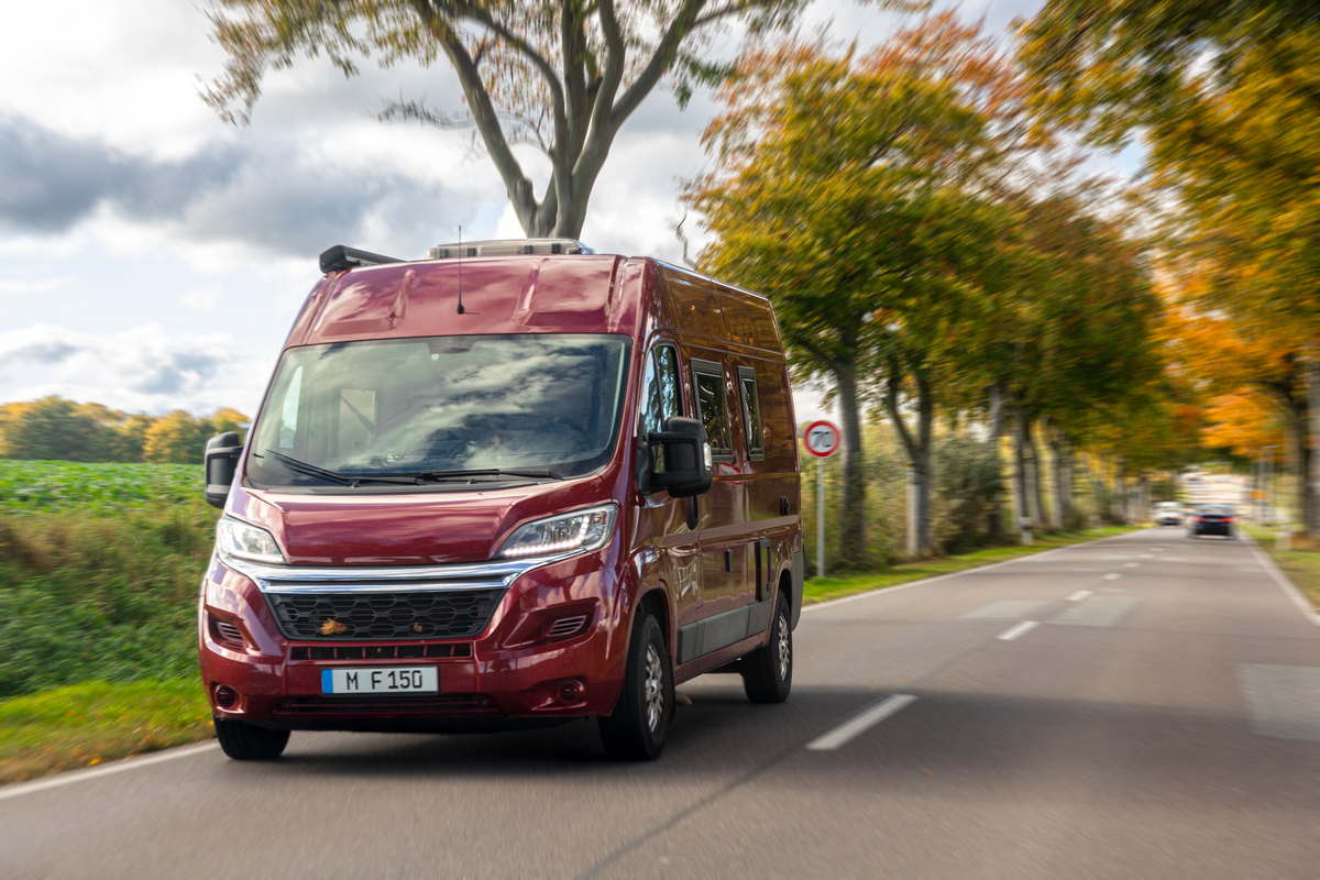 Camper van on scenic road. Autumn travel adventure.